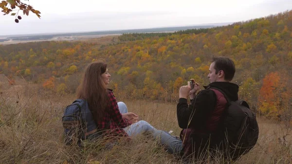 Gratis turister. Man och kvinna med selfie ryggsäckar på toppen av en vacker kulle. Friska resenärer ta bilder på telefon mot bakgrund av vackra landskap. Lagarbete resenärer. äventyrskoncept — Stockfoto