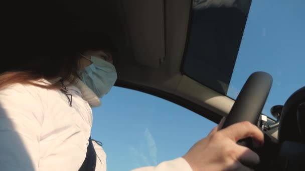 Mulher jovem saudável em máscara médica estéril protetora dirige um carro. conceito de coronavírus pandêmico. menina livre viaja em uma máscara em um carro. proteção contra vírus e bactérias. uma menina monta um carro — Vídeo de Stock