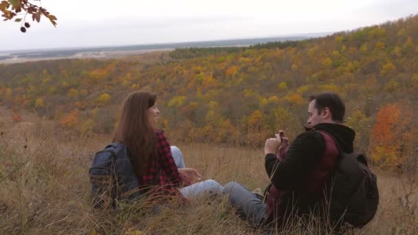 Turisti liberi. Uomo e donna con zaini selfie sulla cima di una bellissima collina. Viaggiatori sani scattano foto al telefono sullo sfondo di un bellissimo paesaggio. viaggiatori di lavoro di squadra. concetto di avventura — Video Stock