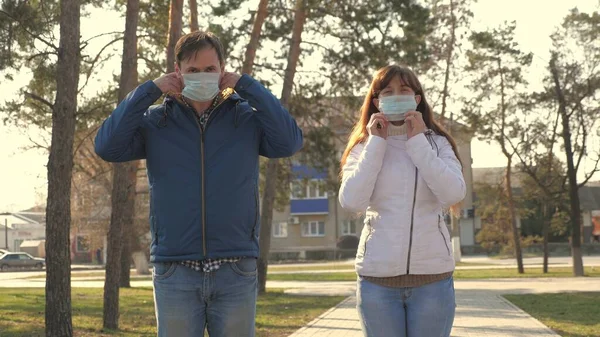 Νεαρό κορίτσι και άντρας φορούν προστατευτική μάσκα στο δρόμο, δείχνοντας έτσι. Οι άνθρωποι φορούν ιατρική μάσκα για τους ιούς, δείχνουν τάξη. Πανδημία Coronavirus έννοια της υγείας και της ασφάλειας, coronavirus N1H1, προστασία του ιού — Φωτογραφία Αρχείου