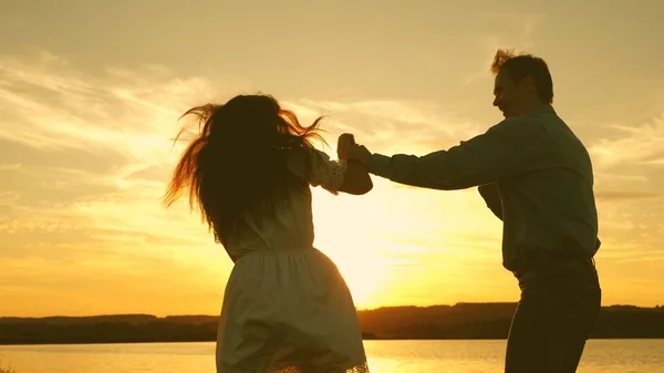 Joyeux garçon et fille valse le soir dans le parc d'été. Un homme et une femme aimants dansent dans des rayons de soleil lumineux sur le fond du lac. Jeune couple dansant au coucher du soleil sur la plage . — Photo