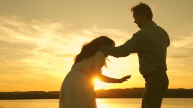 Özgür adam ve kız yaz parkında oynaşıyor. Sağlıklı erkek ve kadın gölün arka planında güneşin parlak ışınlarında oynarlar. Genç çift kumsalda gün batımında eğleniyor..