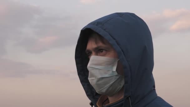 Человек в медицинской защитной маске и капюшоне на одной из улиц города. Пандемия гриппа. Концепция безопасности, коронавирус N1H1, защита от вирусов. Здоровье и безопасность. апокалипсис человечества — стоковое видео
