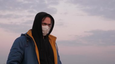 Şehrin caddelerinden birinde tıbbi koruyucu maskeli ve başlıklı bir adam. Grip salgını. Sağlık ve güvenlik konsepti, koronavirüs N1H1, virüs koruması. Sağlık ve güvenlik kavramı. İnsanlığın Kıyameti