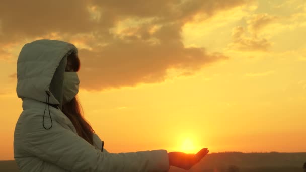 Naděje na uzdravení a zítra. svobodná žena v ochranné lékařské masce drží slunce v jeho rukou při západu slunce. Ochrana proti virům a bakteriím. koncepce bezpečnosti a ochrany zdraví, koronavirus N1H1. — Stock video