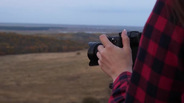 Utazási koncepció. ingyenes lány utazó fényképezőgéppel gyönyörű képeket készít a természetről. független női turista fotós készít képeket egy gyönyörű őszi táj professzionális digitális fényképezőgép — Stock videók
