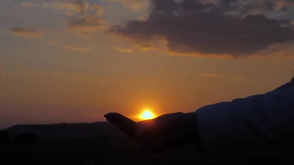 Viajero chica libre sostiene el sol en las palmas. mujer sana viaja y disfruta de la puesta de sol. jugar con el sol. Concepto de viaje y aventura. esperanza y fe en un buen mañana — Foto de Stock