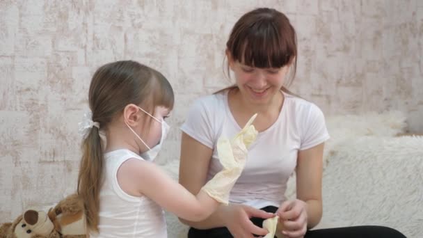 Tıbbi maskeli ve tıbbi eldivenli küçük kız oyuncak ayıyla oynuyor. Koronavirüs ve gribe karşı koruma. Çocuklar hastanede. Çocuk doktor, veteriner, hasta bakıcısı olarak oynuyor.. — Stok video
