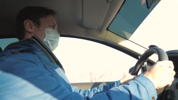 Free man travels in a mask in a car. protection against viruses and bacteria. a boy rides a car. Healthy young guy in protective sterile medical mask drives a car. concept of pandemic coronavirus. — Stock Video