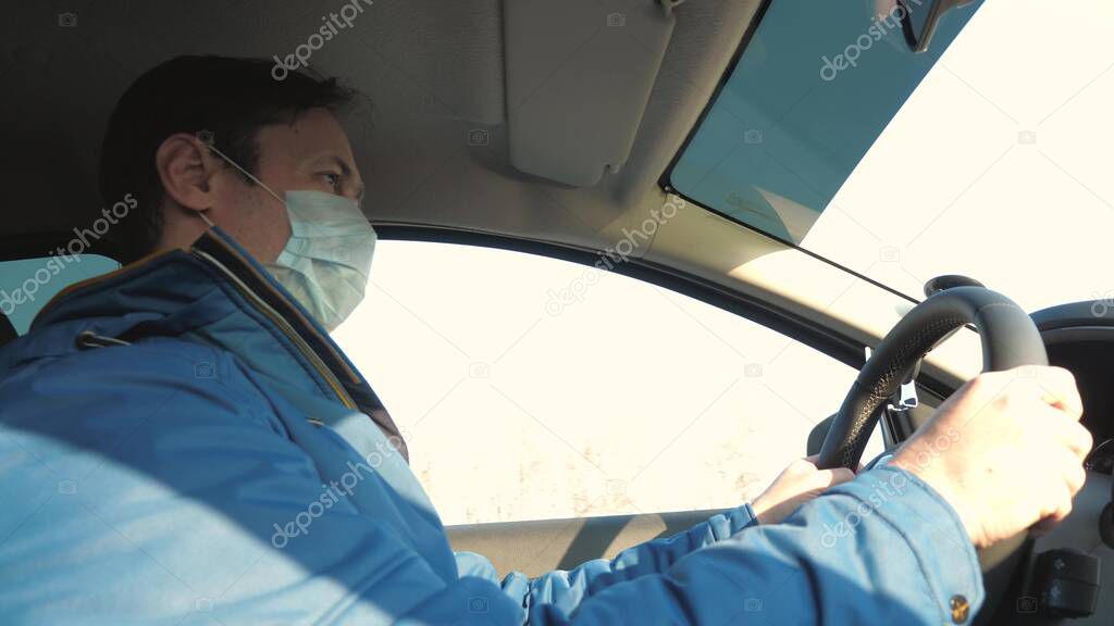 free man travels in a mask in a car. protection against viruses and bacteria. a boy rides a car. Healthy young guy in protective sterile medical mask drives a car. concept of pandemic coronavirus.