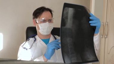 Ofisteki doktor hastanede bir hastanın röntgenini çekiyor. Hastane ofisinde çalışan bir doktor. Tıbbi bakım ve sağlık hizmeti kavramı. Koronavirüs salgını, zatürree COVID-19 tedavisi