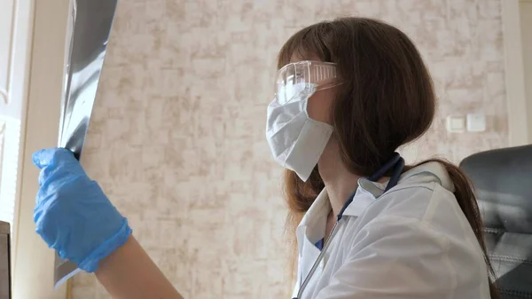 Une femme médecin dans un bureau examine une radiographie d'un patient à l'hôpital. médecin travaille dans le bureau de l'hôpital avec ordinateur portable. Soins médicaux et concept de soins de santé. pandémie de coronovirus, pneumonie COVID-19 — Photo