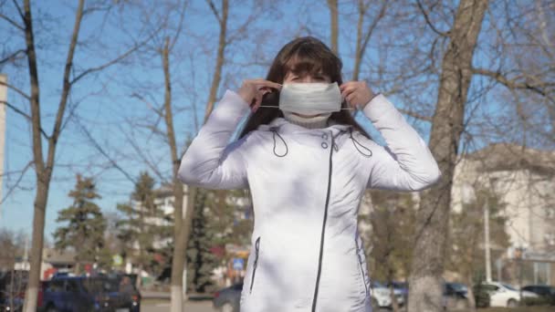 Zdrowa dziewczyna nosząca ochronną maskę medyczną na ulicy, pokazująca się. wolna kobieta nosi maskę medyczną na wirusy i pokazuje klasę. Koncepcja bezpieczeństwa i higieny pracy w przypadku koronawirusu pandemicznego — Wideo stockowe