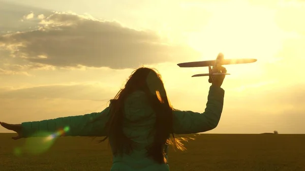 Menina feliz corre com um avião de brinquedo em um campo sob a luz do pôr do sol. As crianças brincam de avião de brinquedo. adolescente sonha em voar e se tornar um piloto. A rapariga quer tornar-se piloto e astronauta. Movimento lento — Fotografia de Stock