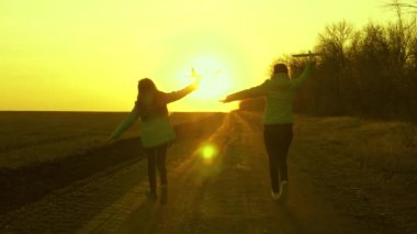 Gün batımında iki kız bir oyuncak uçakla oynuyor. Sağlıklı çocuklar ellerinde bir uçakla yolda koşarlar. Özgür çocukların silueti uçakla oynuyor. Uçma hayalleri. Mutlu çocukluk kavramı.