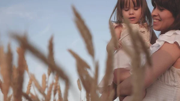 Maman et petite fille jouent sur un champ de blé mûr au soleil. mère marche avec un enfant dans un champ avec du blé. famille heureuse voyage. bébé dans les bras de maman. concept de famille heureuse . — Photo