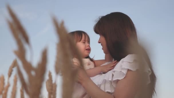 Máma a dcerka si hrají na poli zralý pšenice na slunci. matka chodí s dítětem na poli s pšenicí. Šťastná rodina cestuje. dítě v náručí mámy. šťastný rodinný koncept. — Stock video