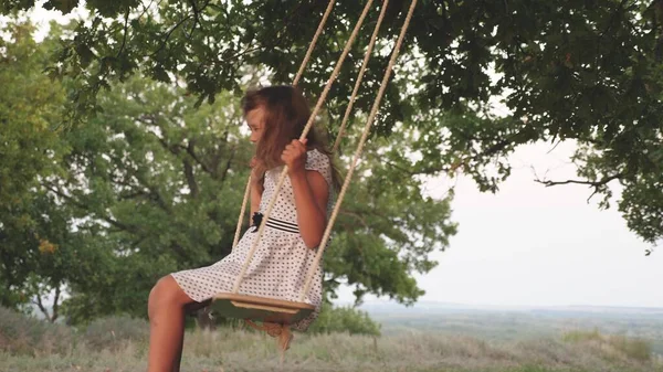 Madre juega con su hija en un columpio en una rama de roble. niño sano de la familia y mamá balanceándose en un columpio en el parque. chica libre le encanta volar en columpio en el bosque. concepto de familia feliz y la infancia . —  Fotos de Stock