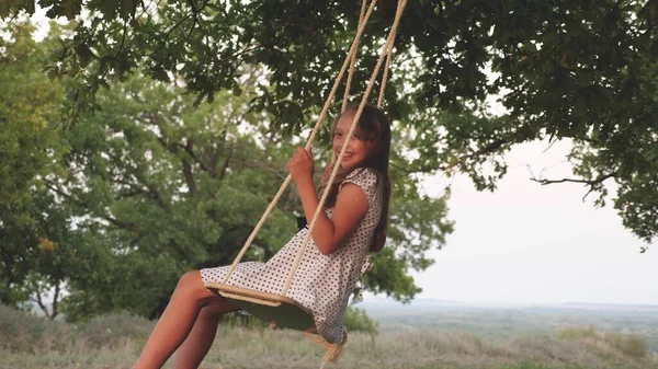 Moeder speelt met haar dochter op een schommel op een eiken tak. gezond gezin kind en moeder swingen op een schommel in het park. vrij meisje houdt van vliegen op swing in bos. concept van gelukkig gezin en jeugd. — Stockfoto