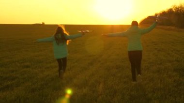 Sağlıklı çocuklar ellerinde uçakla güneşte koşarlar. Özgür kızlar gün batımında oyuncak bir uçakla oynarlar. Uçma hayalleri. Mutlu çocukluk kavramı. Uçakta oynayan çocukların silueti