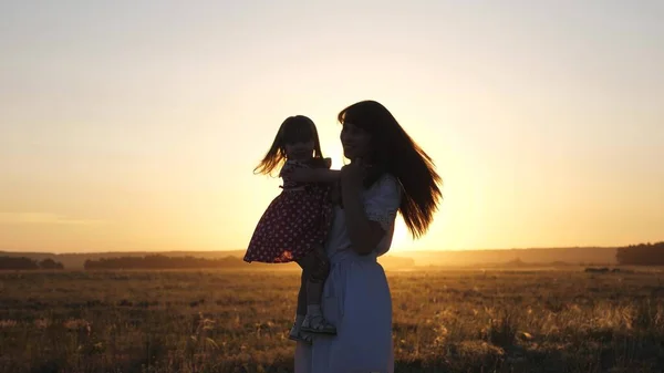 Η ελεύθερη μαμά και η μικρή κόρη χορεύουν στο ηλιοβασίλεμα. Μητέρα και υγιές μωρό στην αγκαλιά της στο χωράφι. έννοια της ευτυχισμένης παιδικής ηλικίας. Το χαρούμενο παιδί παίζει με τη μητέρα του το ηλιοβασίλεμα. χαρούμενη οικογενειακή έννοια — Φωτογραφία Αρχείου