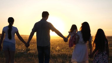 Özgür Mutlu Aile gün batımında tarlada yürüyor. Sağlıklı baba ve kızları gün ışığında parkta yürürler. Çocuklar ve ebeveynler tatile çıkar. Mutlu baba bir çocuk taşıyor. Mutlu çocukluk ve