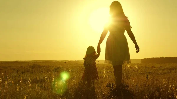 Familia feliz libre con un niño camina en el campo. madre sana y el bebé están descansando en el parque. Feliz infancia. hija pequeña y madre caminan por el campo tomados de la mano. bebé sostiene las mamás mano . —  Fotos de Stock