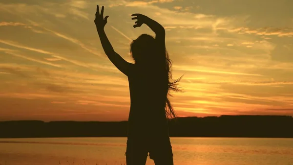 Chica libre bailando al atardecer con el pelo largo en los rayos de la puesta del sol. mujer sana bailando en la fiesta de la playa. Baile de noche en la orilla del mar. En cámara lenta. chica viajero, turista está bailando —  Fotos de Stock