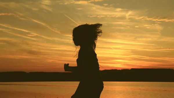 Freies Mädchen, das bei Sonnenuntergang mit langen Haaren in den Strahlen des Sonnenuntergangs tanzt. Gesunde Frau tanzt auf der Beachparty. Abendliches Tanzen am Meer. Zeitlupe. Reiseleiterin, Touristin tanzt — Stockfoto