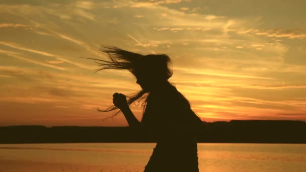 Chica libre bailando al atardecer con el pelo largo en los rayos de la puesta del sol. mujer sana bailando en la fiesta de la playa. Baile de noche en la orilla del mar. En cámara lenta. chica viajero, turista está bailando — Vídeos de Stock