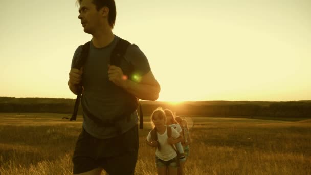 L'arrampicatore aiuta i turisti a conquistare la cima della montagna, si allungano e si tirano l'un l'altro verso la cima. lavoro di squadra di viaggiatori liberi. padre sano, madre figlia turisti. Famiglia con bambini viaggia . — Video Stock