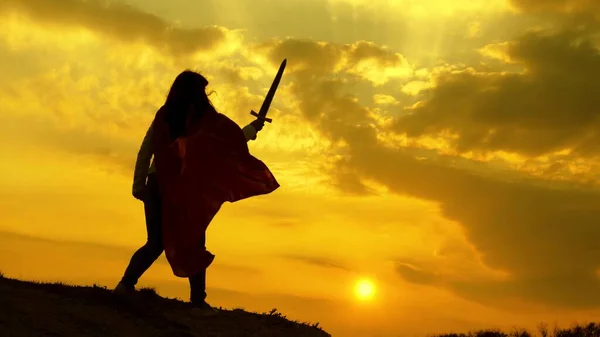 Kırmızı pelerinli süper kadın gün batımında bir dağda savaşmayı hayal ediyor. Özgür kadın süper kahramanı oynuyor. Kız, Roma Lenin 'ini güneşin parlak ışınlarıyla gökyüzüne karşı oynuyor.