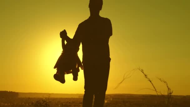 Father and little daughter whirl in dance at sunset. concept of happy childhood. Dad is dancing with child in her arms. happy child plays with his father at sunset. concept of a happy family — Stock Video