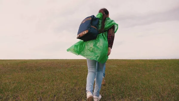 Turist kızlar tepeye tırmanan çok renkli yağmurluklarla sırt çantasıyla seyahat ederler. Özgür kadın gezginler el ele dağın zirvesine çıkar. Ağır çekim. Takım çalışması gezginleri. macera konsepti. — Stok fotoğraf