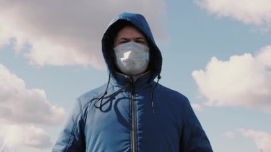 Kapüşonlu adam şehirde bir sokakta tıbbi koruyucu maske takıyor. Yakın plan. Sağlık ve güvenlik konsepti, koronavirüs N1H1, virüs koruması. Sağlık ve güvenlik kavramı. Grip salgını.