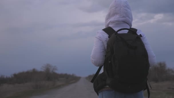 Viaggiatore ragazza libera con uno zaino in maschera medica protettiva e cappuccio è a piedi fuori città su strada. Protezione contro virus e batteri. concetto di salute e sicurezza, coronavirus N1H1, virus — Video Stock