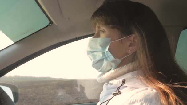 Chica libre viaja en una máscara en un coche. protección contra virus y bacterias. una chica monta un coche. Mujer joven y saludable en máscara médica estéril protectora conduce un coche . — Vídeos de Stock