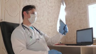 Koronavirüs salgını, zatürree COVID-19 tedavisi. Ofisteki doktor hastanede bir hastanın röntgenini çekiyor. Hastane ofisinde çalışan bir doktor. Tıbbi bakım ve sağlık hizmeti kavramı.