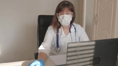 Beyaz önlüklü ve güvenlik gözlüklü kadın doktor dizüstü bilgisayar, online danışma ve konferans üzerinde çalışıyor. Doktor sanal sohbet kullanarak bir müşteriyle iletişim kuruyor. Teletıp, uzaktan tıbbi bakım konsepti.