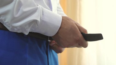 Erkeklerin elleri mavi pantolona kemer takar. Bir adam yakından giyinir. Genç işadamı bir iş toplantısına gidiyor. Bir adam işe gitmek için sabahları giyinir. ofis çalışanı.