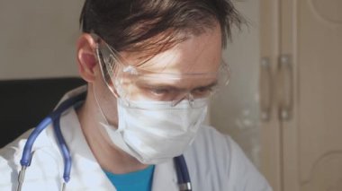 Doktor müşterisiyle uzaktan bilgisayar aracılığıyla çalışır. Beyaz önlüklü ve güvenlik gözlüklü bir doktor dizüstü bilgisayar, online danışma ve konferans üzerinde çalışıyor. Teletıp, uzaktan tıbbi bakım konsepti
