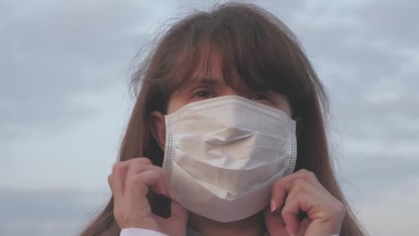 Бесплатная здоровая женщина надевает защитную медицинскую маску на улице. Защита от вирусов и бактерий. концепция безопасности и здоровья, коронавирус N1H1, защита. туристическая девушка в маске — стоковое видео