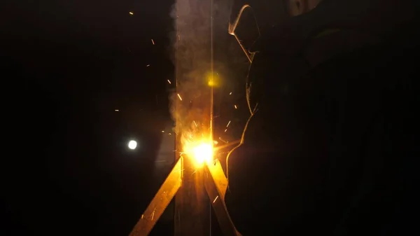 明るい光と溶接から火花。金属加工工場の工業生産における金属構造物の溶接に近代的な溶接機を使用した保護マスクの産業労働者. — ストック写真