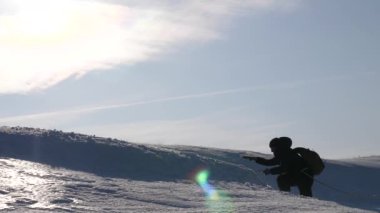 Kışın üç dağcı dağda ipe tırmanıyor. Gezginler, güçlü bir rüzgarda kar altında zaferlerine giden ipleri tırmanırlar. Turistler kışın birlikte çalışarak zorlukların üstesinden gelirler. takım çalışması