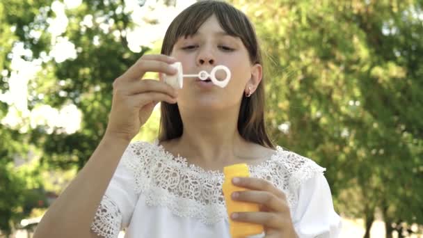 Gratis meisje blazen zeepbellen in het park in het voorjaar, zomer en glimlachen. jong gezond meisje spelen in het park en blazen bubbels in de camera lens. Langzame beweging. — Stockvideo