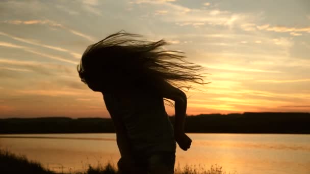 女の子旅行者観光客が踊っています。夕日の光の中で長い髪で夕暮れ時に踊るフリーガール。ビーチパーティーで踊ってる健康な女性。夜は海岸で踊ります。スローモーション. — ストック動画