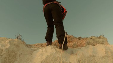 Dağcı bir iple dağdan iner. Gün batımında dağlarda seyahat ve macera. Turistlerin takım çalışması. İş adamları birbirlerini sigortalarlar. Zor durumlarda yardım.