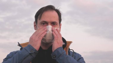 Özgür erkek gezgin gün batımında koruyucu bir tıbbi maske takıyor. Koruyucu maskeli bir turist. Sağlık ve güvenlik konsepti, koronavirüs N1H1, koruma. Virüs ve bakterilere karşı koruma.