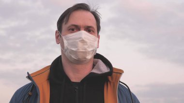 Özgür erkek gezgin gün batımında koruyucu bir tıbbi maske takıyor. Koruyucu maskeli bir turist. Sağlık ve güvenlik konsepti, koronavirüs N1H1, koruma. Virüs ve bakterilere karşı koruma.