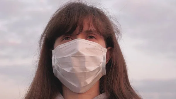 Frisk flicka i en skyddande mask. fri kvinna bär en skyddande medicinsk mask i solnedgången ljus. Skydd mot virus och bakterier. hälso- och säkerhetskoncept, coronavirus N1H1, skydd. — Stockfoto